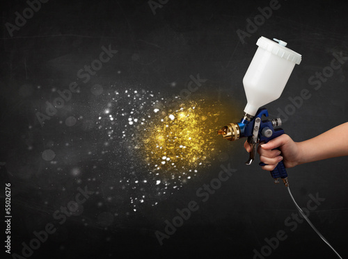 Worker with airbrush painting with glowing golden paint photo