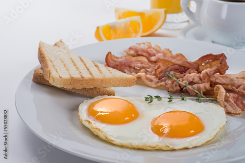 Close-up of a plate with fried eggs, bacon and toasts