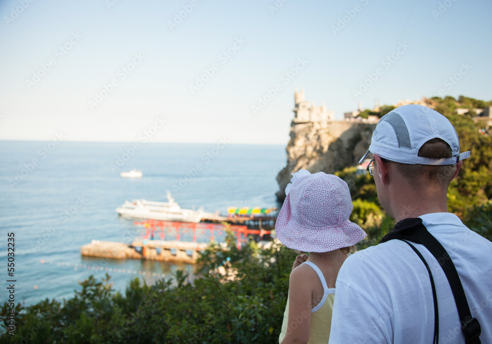 Young father and his little daughter looking at the sea