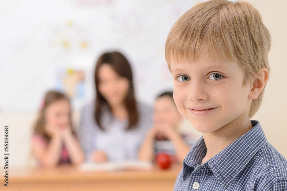 Schoolboy. Cheerful schoolboy smiling at camera while teacher wi Schoolboy. Cheerful schoolboy smiling at camera while teacher wi