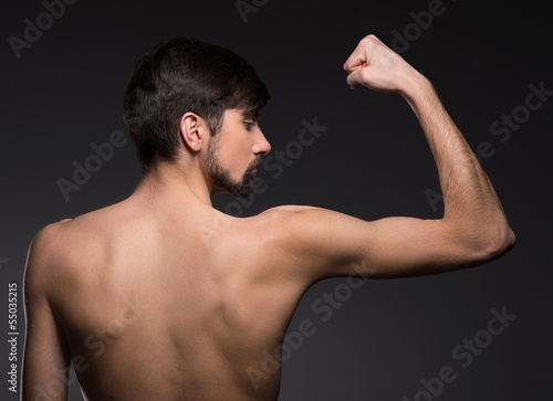 Strong young man. Rear view of shirtless man posing while isolat