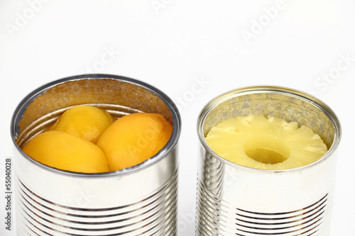 The tins with peaches and pineapples on the white background
