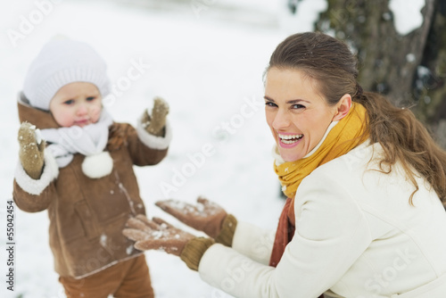 Happy mother playing with baby in winter park © Alliance