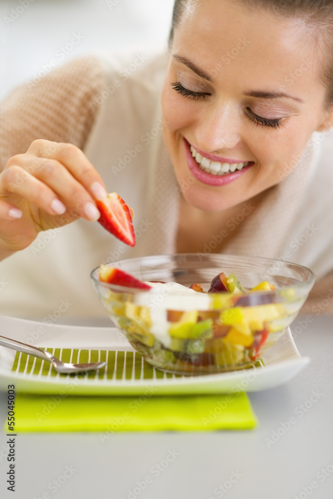 Happy young housewife decorating fruits salad Happy young housewife decorating fruits salad