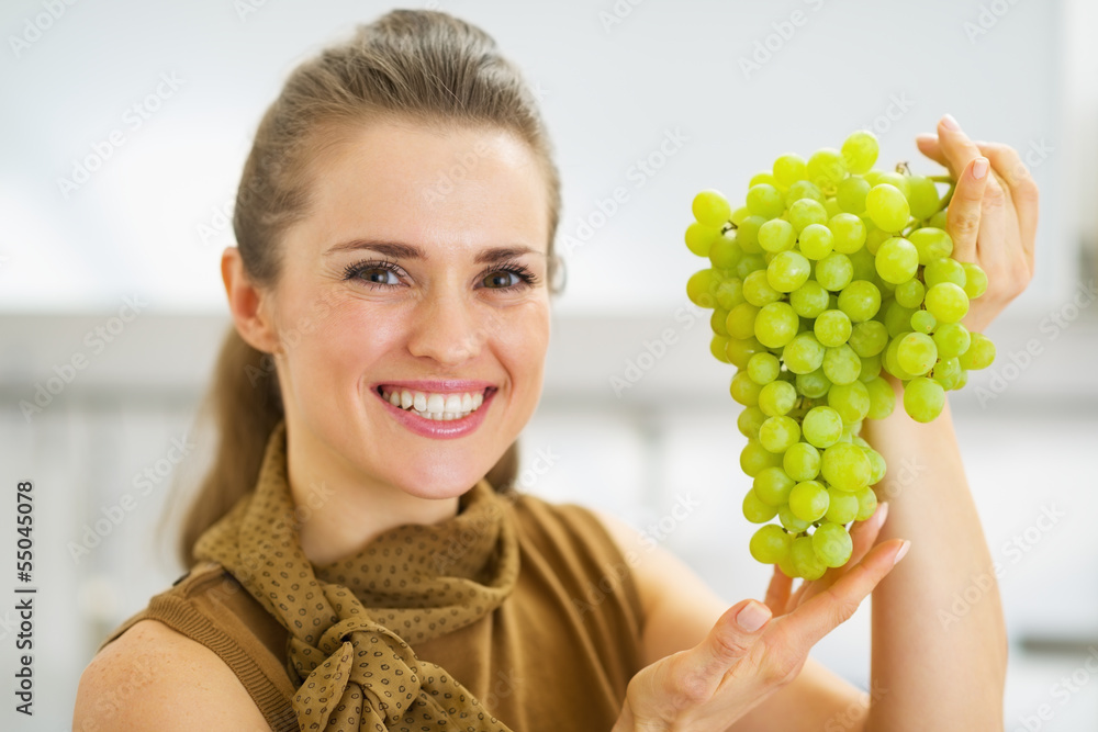Portrait of smiling young housewife showing branch of grapes Portrait of smiling young housewife showing branch of grapes