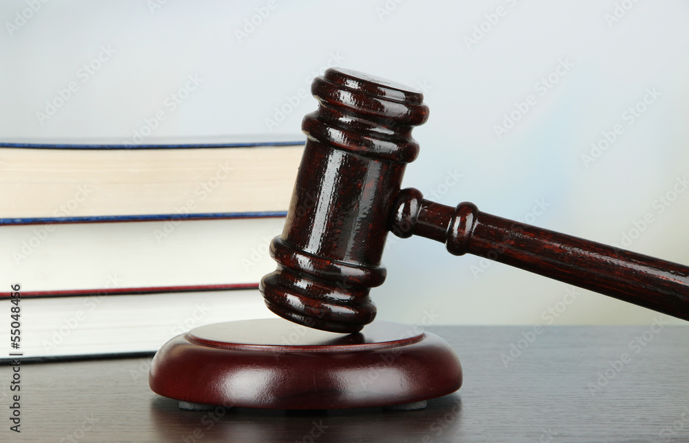 Gavel and books on table on light background