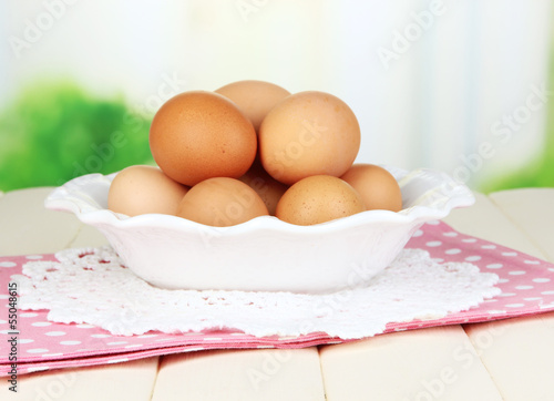 Eggs in plate on wooden table on natural background