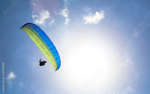 Paraglider hovers in a sunny blue sky