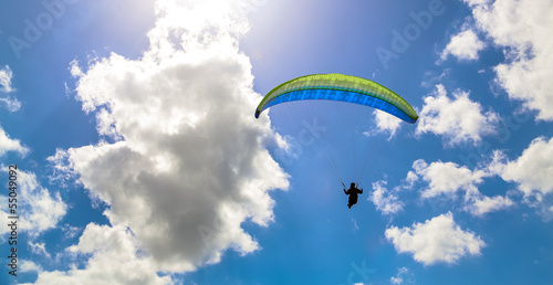 Paraglider hovers in a sunny blue sky