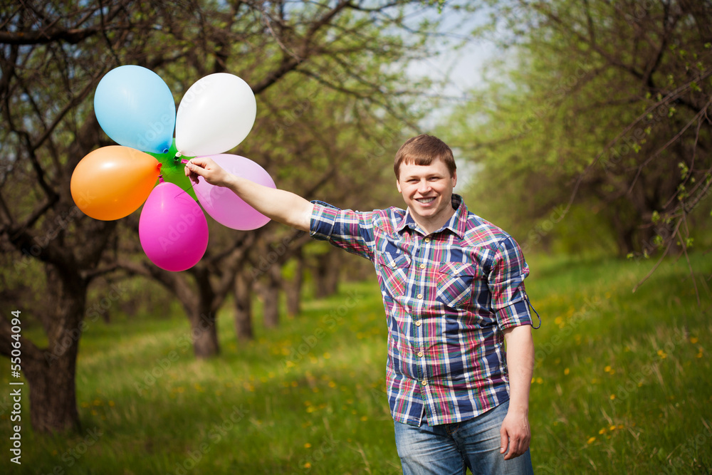 man with balloons on the green spring meadow