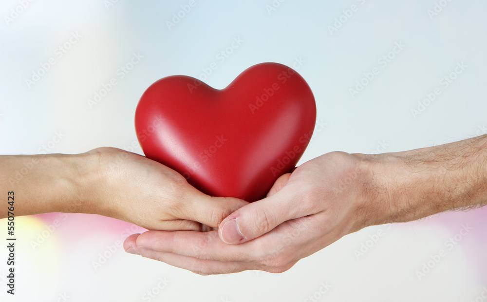 Heart in hands on light background