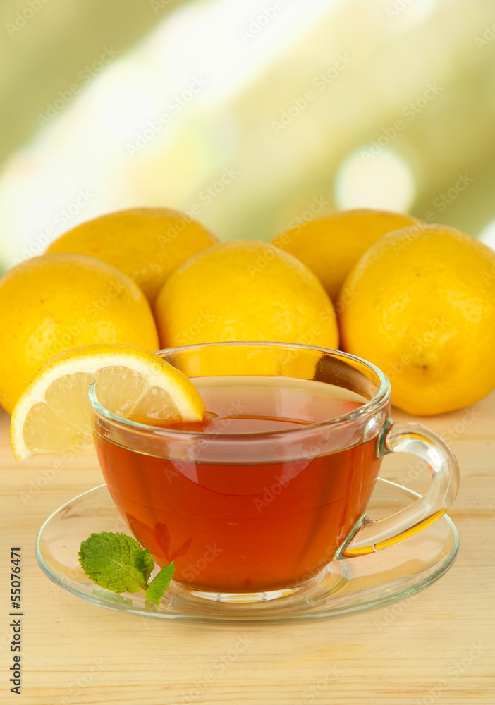 Cup of tea with lemon on table on light background