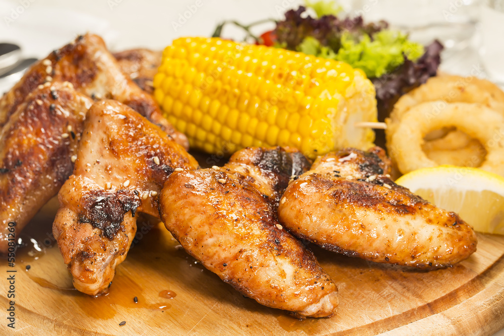 chicken wings are grilled on a wooden platter chicken wings are grilled on a wooden platter