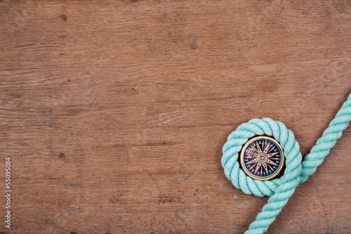 Compass and rope on wooden texture background