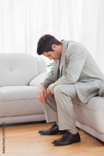 Troubled buinessman sitting on sofa lowering his head © WavebreakmediaMicro