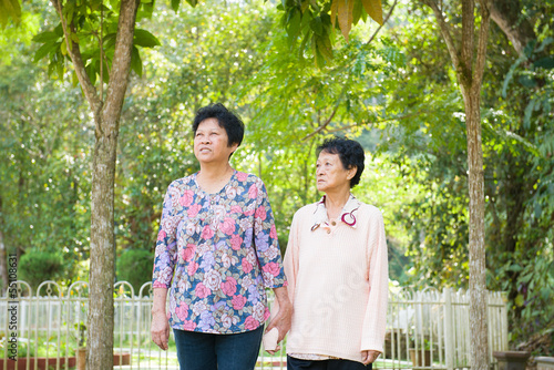 Canvas Print asian senior daughter holding hands walking at outdoor park.
