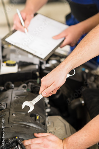 Hands of car mechanic pointing with wrench