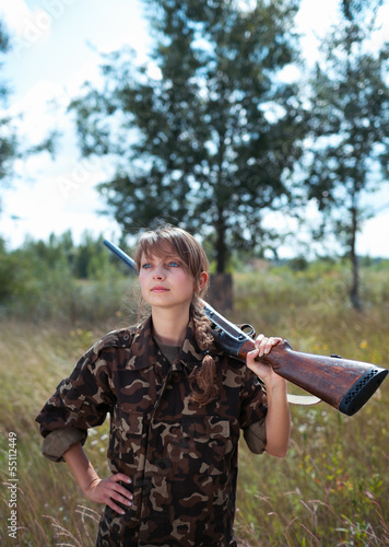 Young beautiful girl with a shotgun in an outdoo