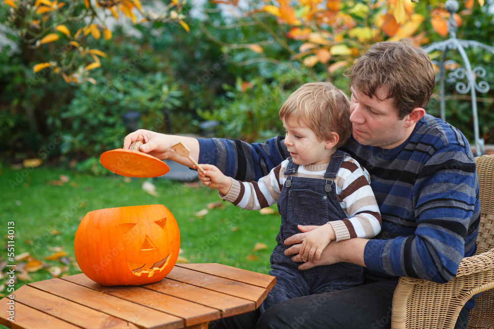 Fototapeta premium Young man and toddler boy making halloween pumpkin