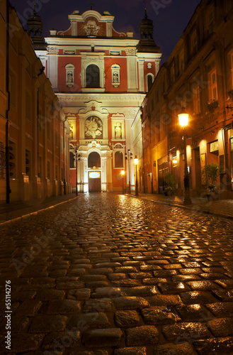 Paved street and parish church in Poznan by night. © GKor