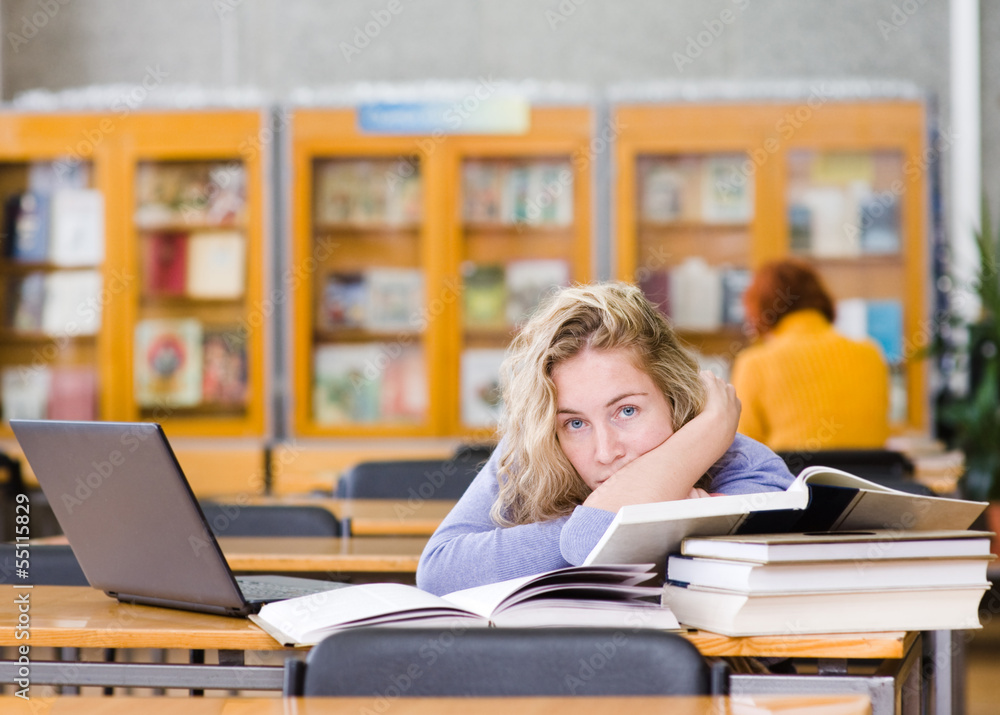tired student in a university library. looking at camera tired student in a university library. looking at camera