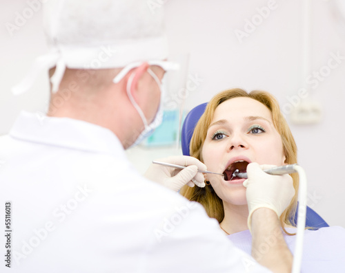 young woman with open mouth during drilling treatment at the den