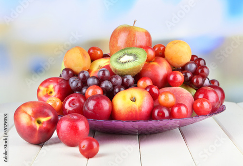 Assortment of juicy fruits on wooden table, on bright