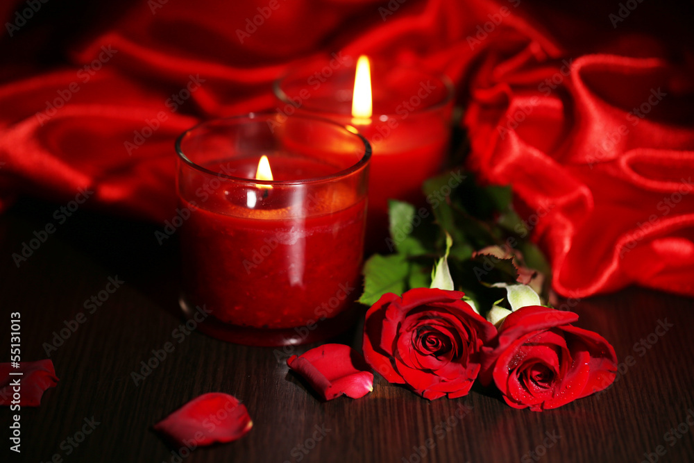 Fototapeta premium Piękna romantyczna czerwona świeca z kwiatami i jedwabnym materiałem,