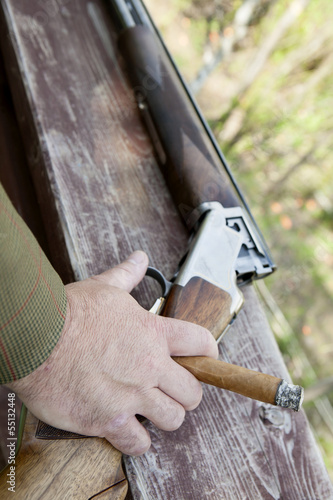 Male hand holding cigar with handgun in background