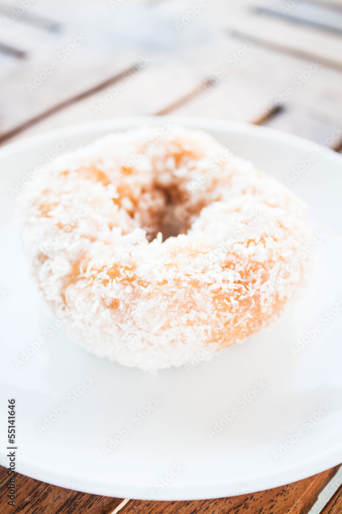 Piece of vanilla coconut donut on white plate
