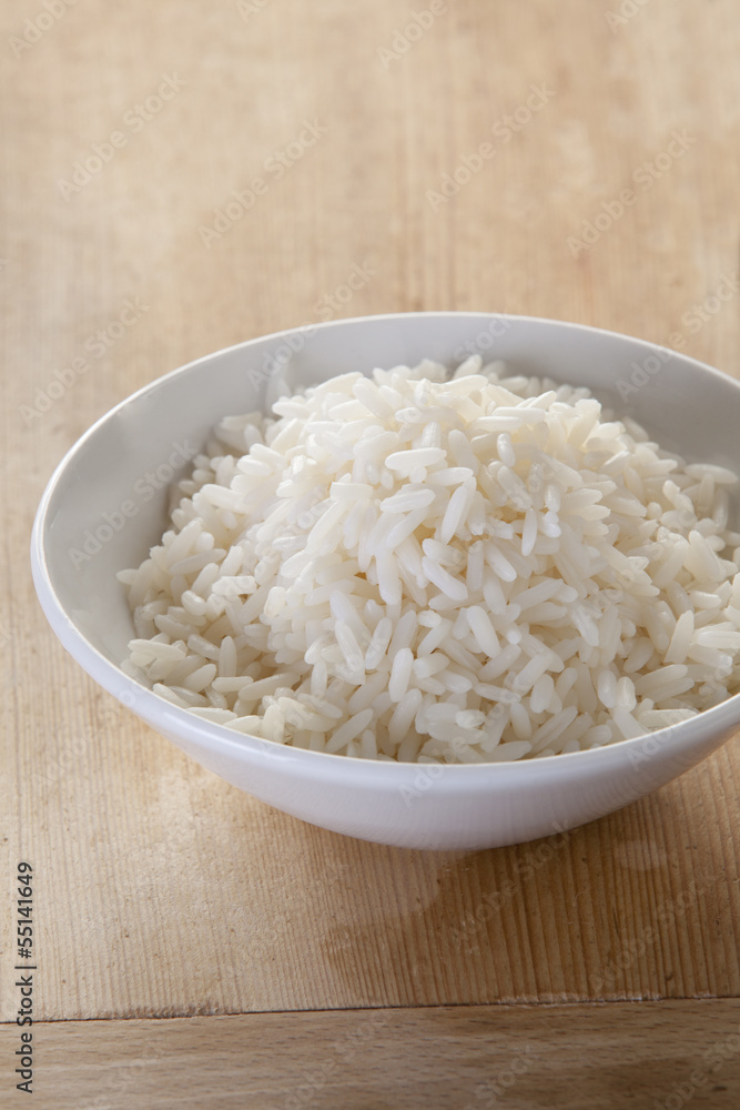 White rice in a bowl on a rustic wooden background White rice in a bowl on a rustic wooden background
