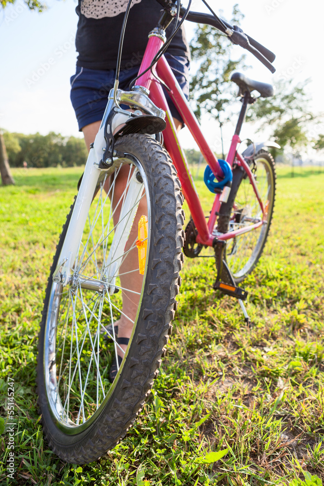 Fototapeta premium Unrecognizable woman holding a bicycle standing against the sun