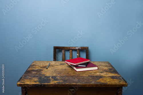 Obraz na płótnie Old wooden desk and chair with books and a pen