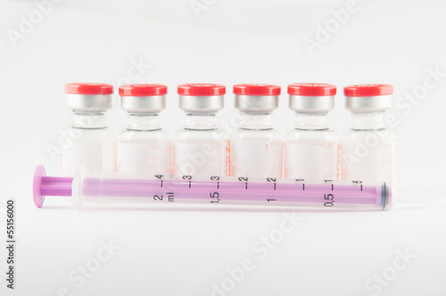 Disposable syringe in front red cap injection vials background