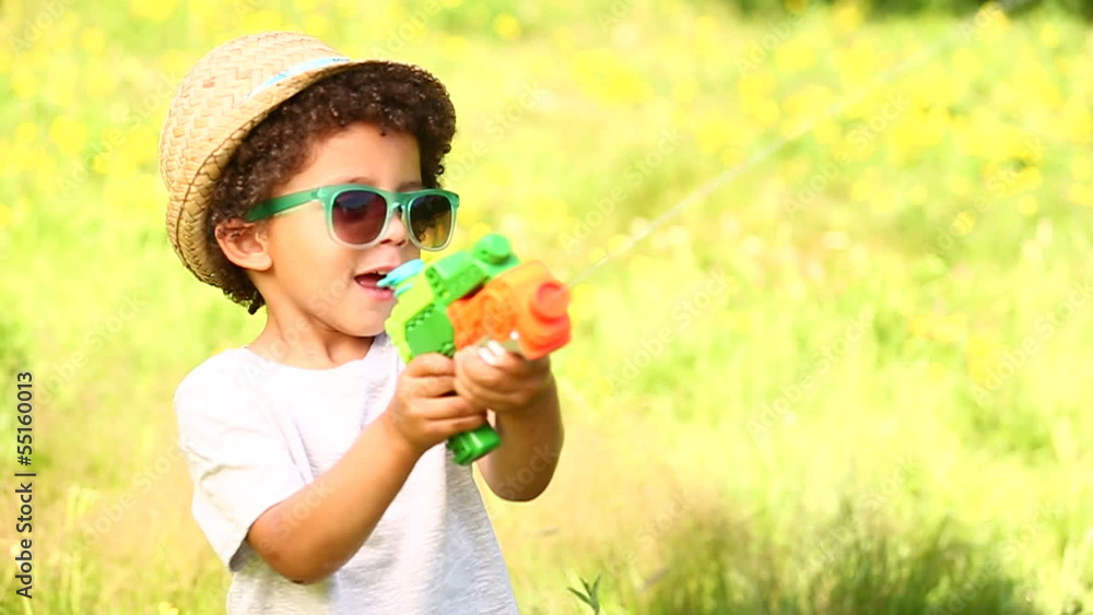 Little boy smiling while using water pistol Little boy smiling while using water pistol