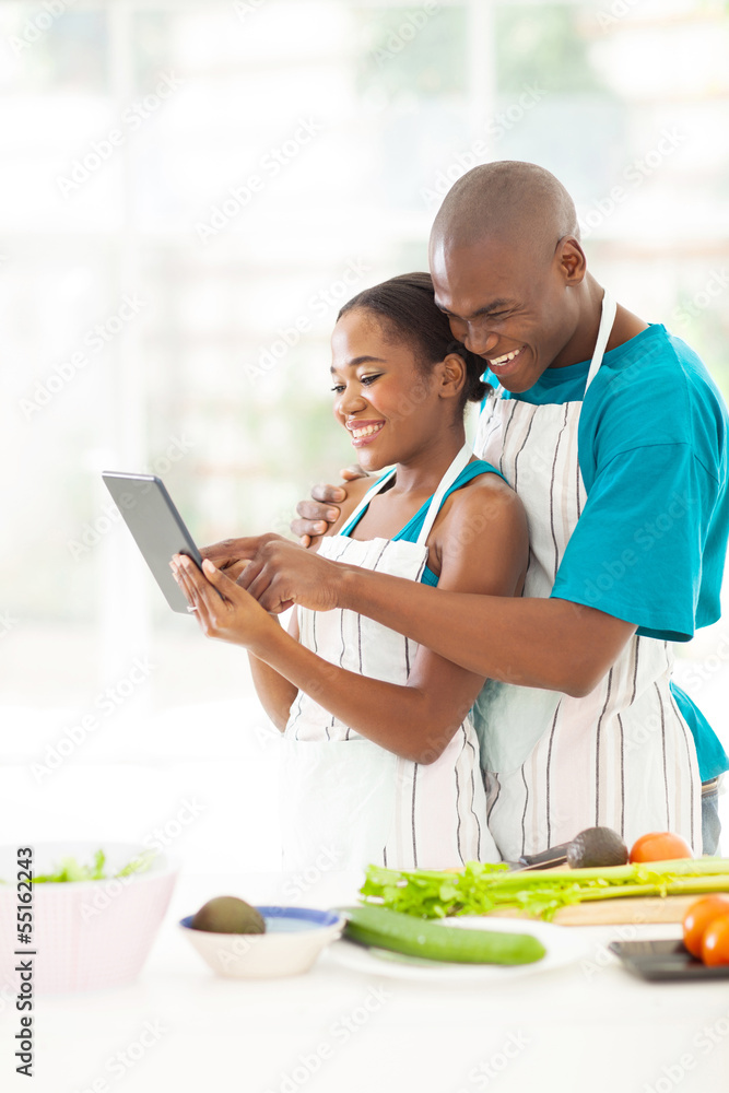 african couple using tablet computer in kitchen african couple using tablet computer in kitchen