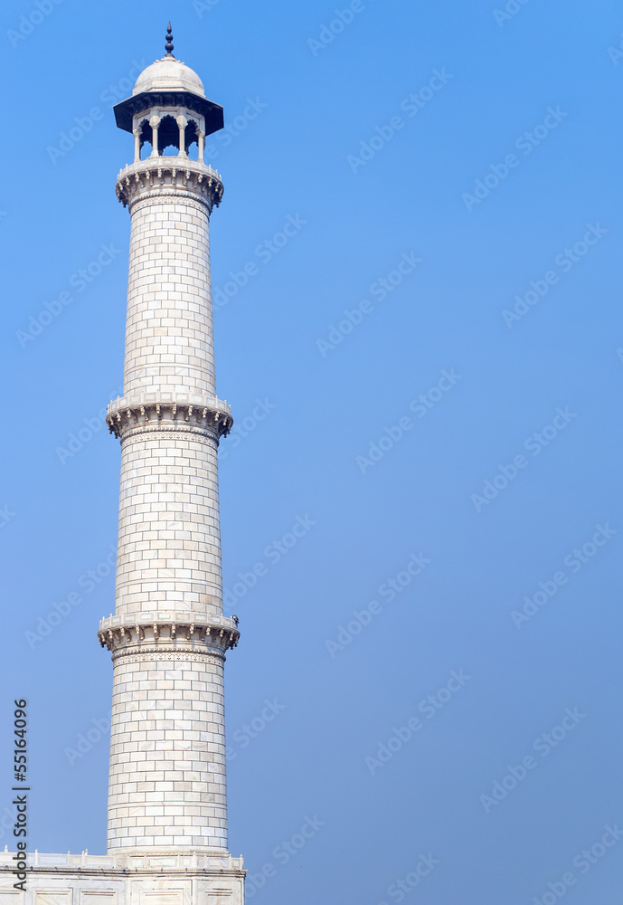 One of the four Taj Mahal minarets against blue sky in India's A