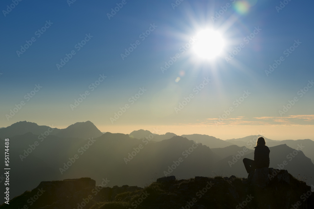 lonely thinking person on peak of mountain at sunset