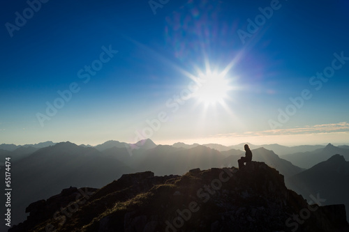 lonely sad girl sitting on rock at sunset mountains