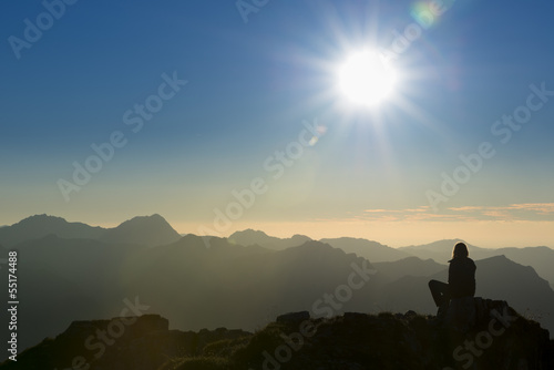 lonely thinking person on peak of mountain at sunset