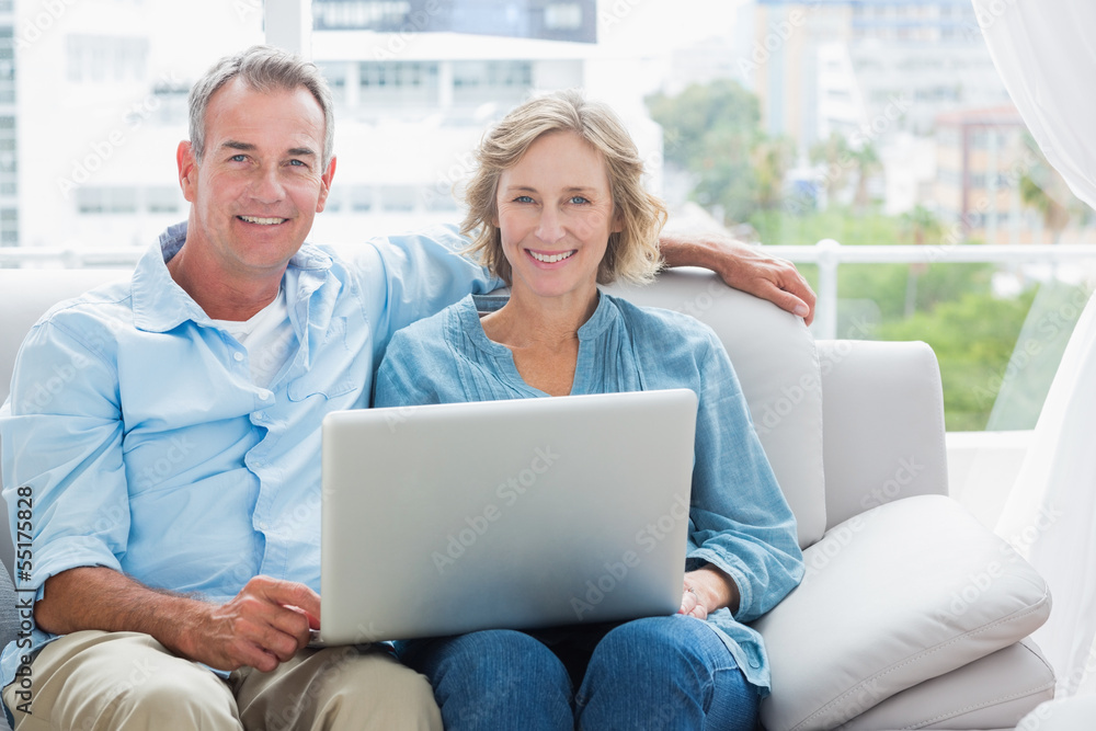 Happy couple relaxing on their couch using the laptop Happy couple relaxing on their couch using the laptop