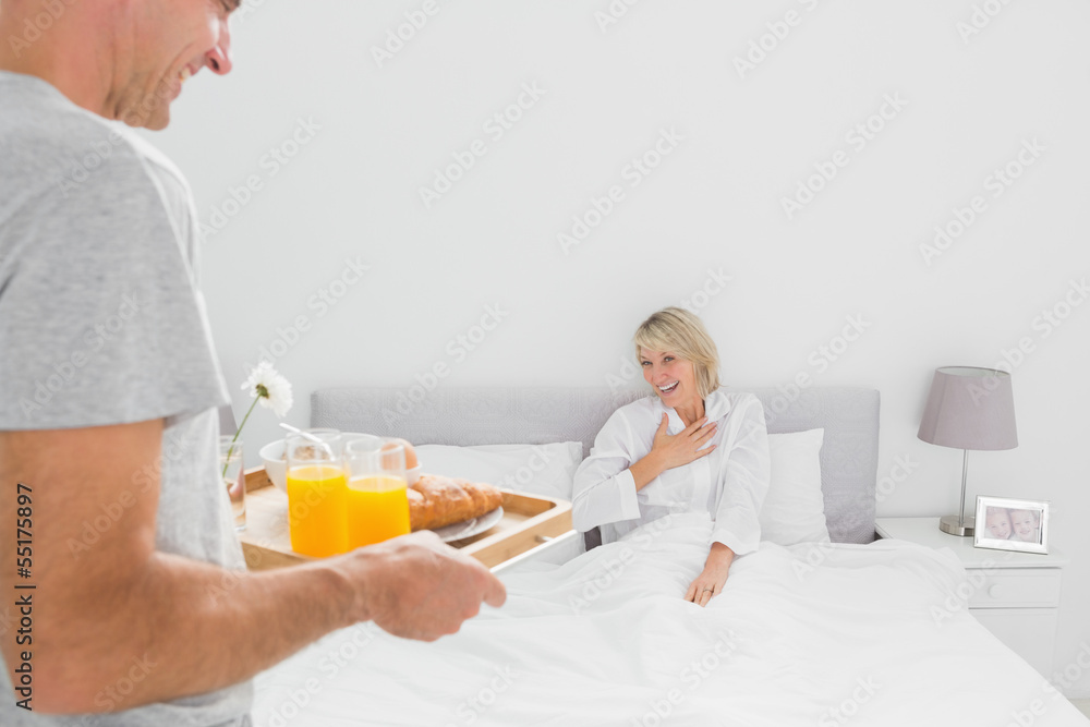 Man bringing breakfast in bed to his partner Man bringing breakfast in bed to his partner