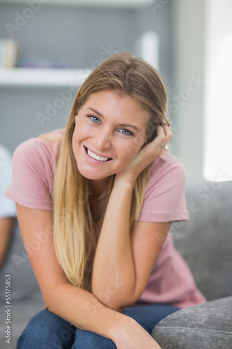 Happy woman sitting on couch looking at camera