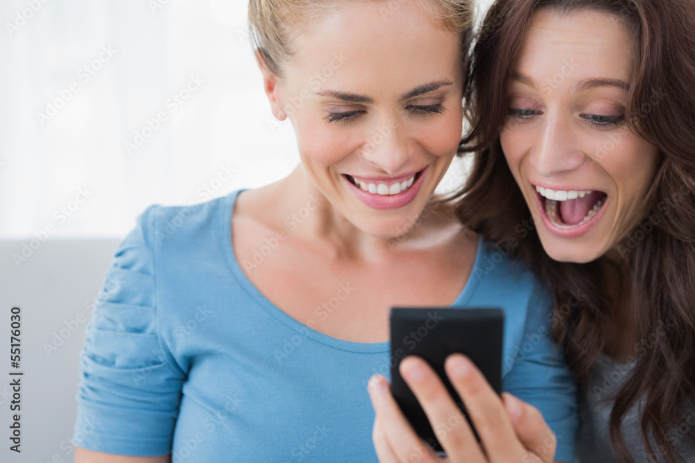 Cheerful friends reading message on their phone Cheerful friends reading message on their phone