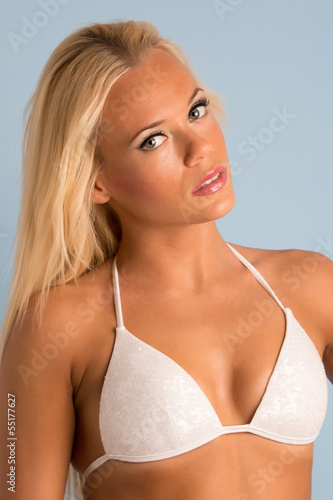 blonde girl in white swimwear. portrait on azure background