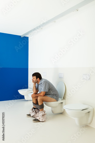 Man sitting on the toilet, public bathroom