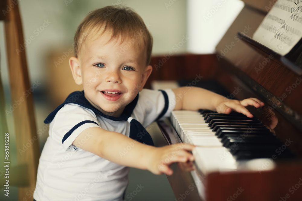 Fototapeta little funny boy plays piano
