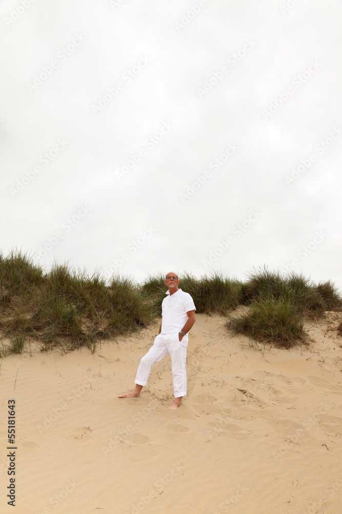 Retired man with beard and glasses outdoors in grass dune landsc Retired man with beard and glasses outdoors in grass dune landsc