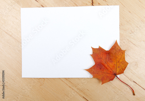 Autumn leave with paper sheet on wooden background texture