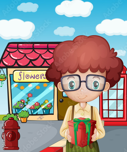 A boy holding a gift in front of the flower shop